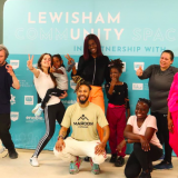 Group of people in workout clothes smiling and posing in front of blue banner that reads Lewisham CommUNITY