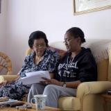Older woman and younger woman sat on a sofa, talking